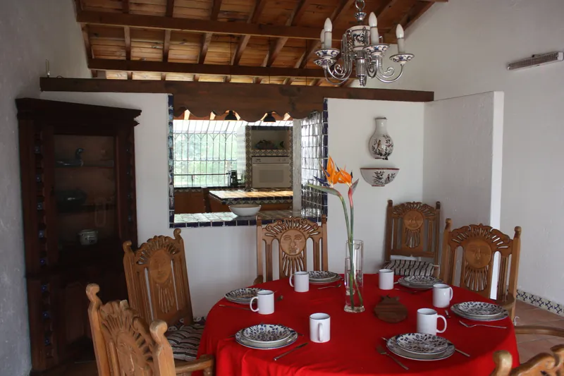 Comedor con mesa servida, sillas de madera y candil