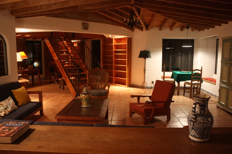 Sala con sillones, techo de viga y la escalera al tapanco al fondo