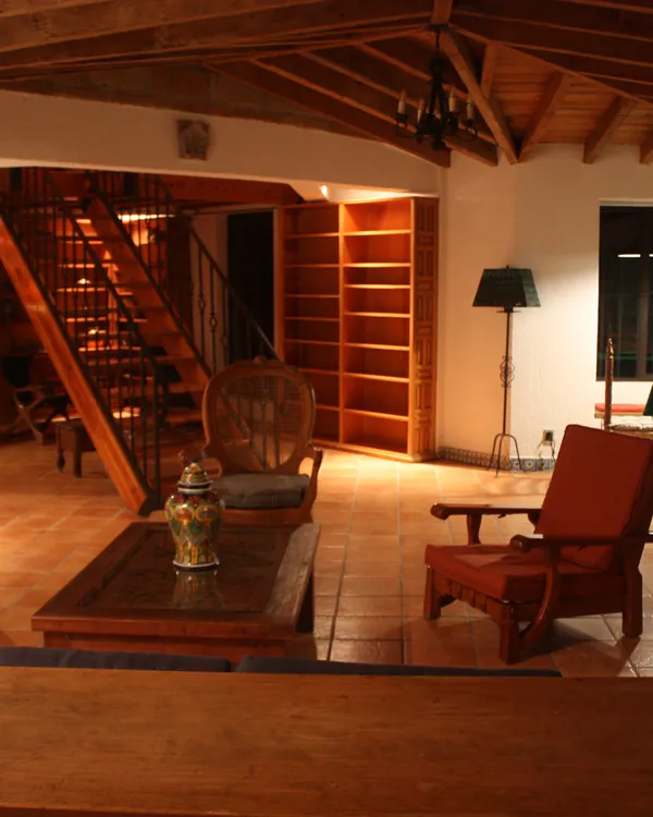 Sala con sillones, techo de viga y la escalera al tapanco al fondo