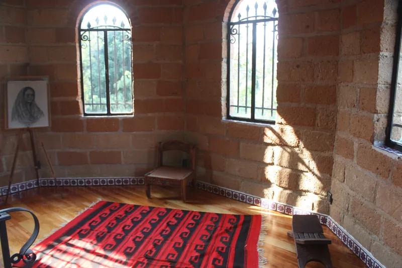 Tapanco con muros de ladrillo, ventanas en arco y tapete rojo