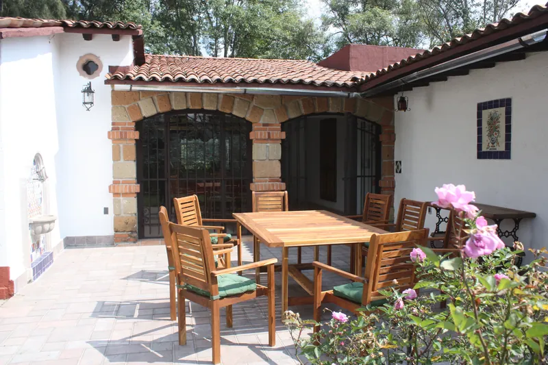 Terraza con mesa de madera frente a los arcos de la casa
