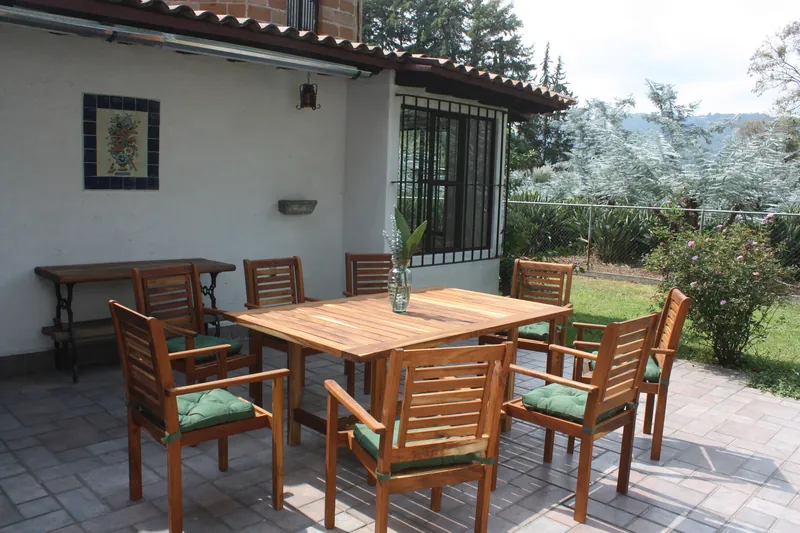 Comedor exterior de madera en la terraza, frente al jardín